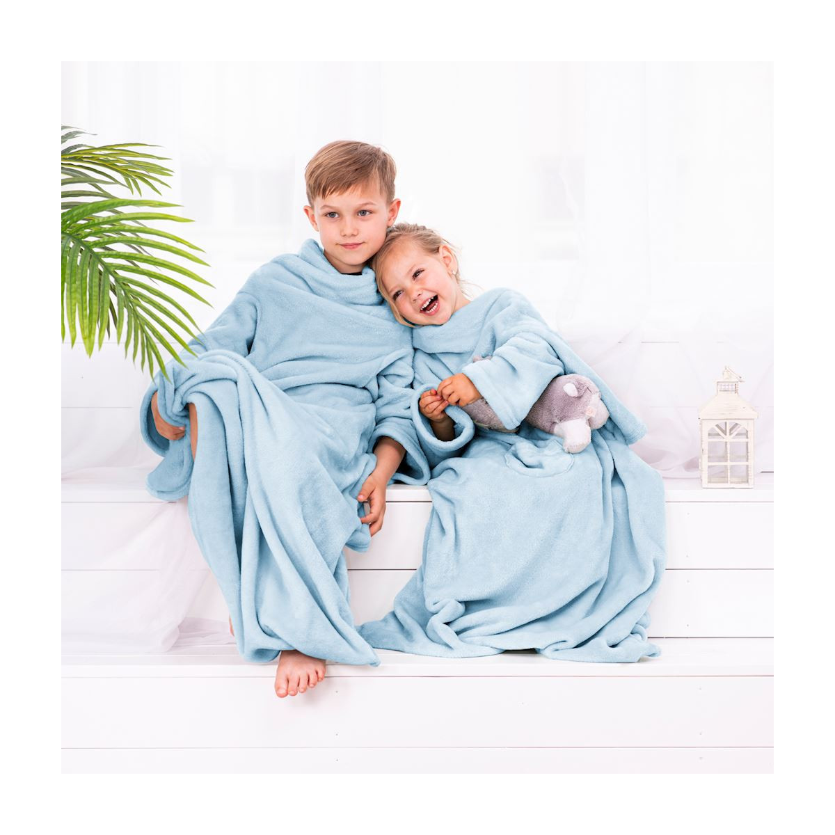 Pătură modernă pentru copii, de culoare albastră, cu mâneci, cu dimensiunile 90x105 cm.