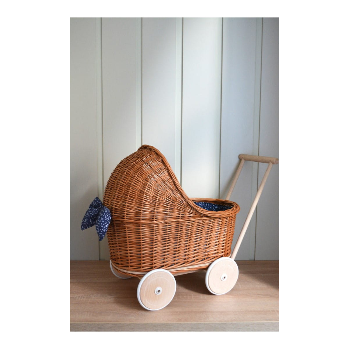 Cărucioare din rattan pentru copii, de culoare maro, cu o păturică albastră.