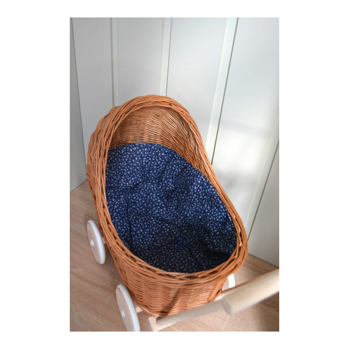 Cărucioare din rattan pentru copii, de culoare maro, cu o păturică albastră.