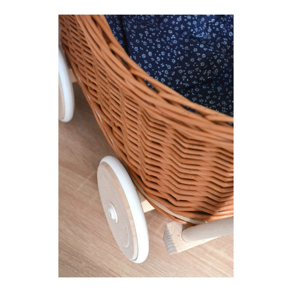 Cărucioare din rattan pentru copii, de culoare maro, cu o păturică albastră.