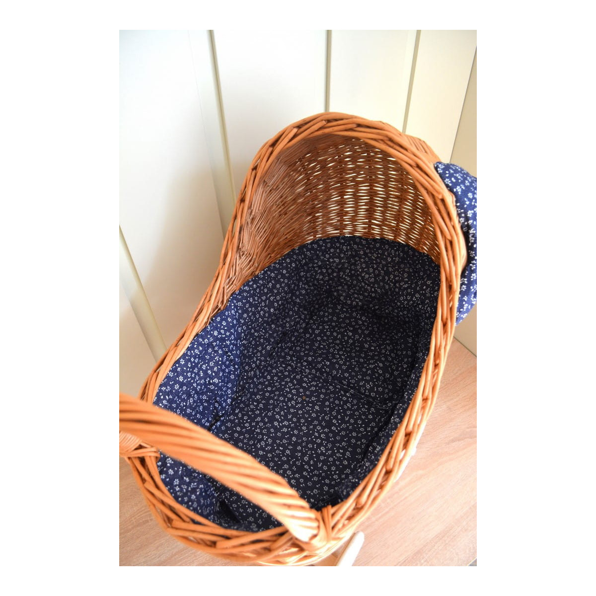 Cărucior din rattan pentru copii, cu fundiță albastră și roți din cauciuc.