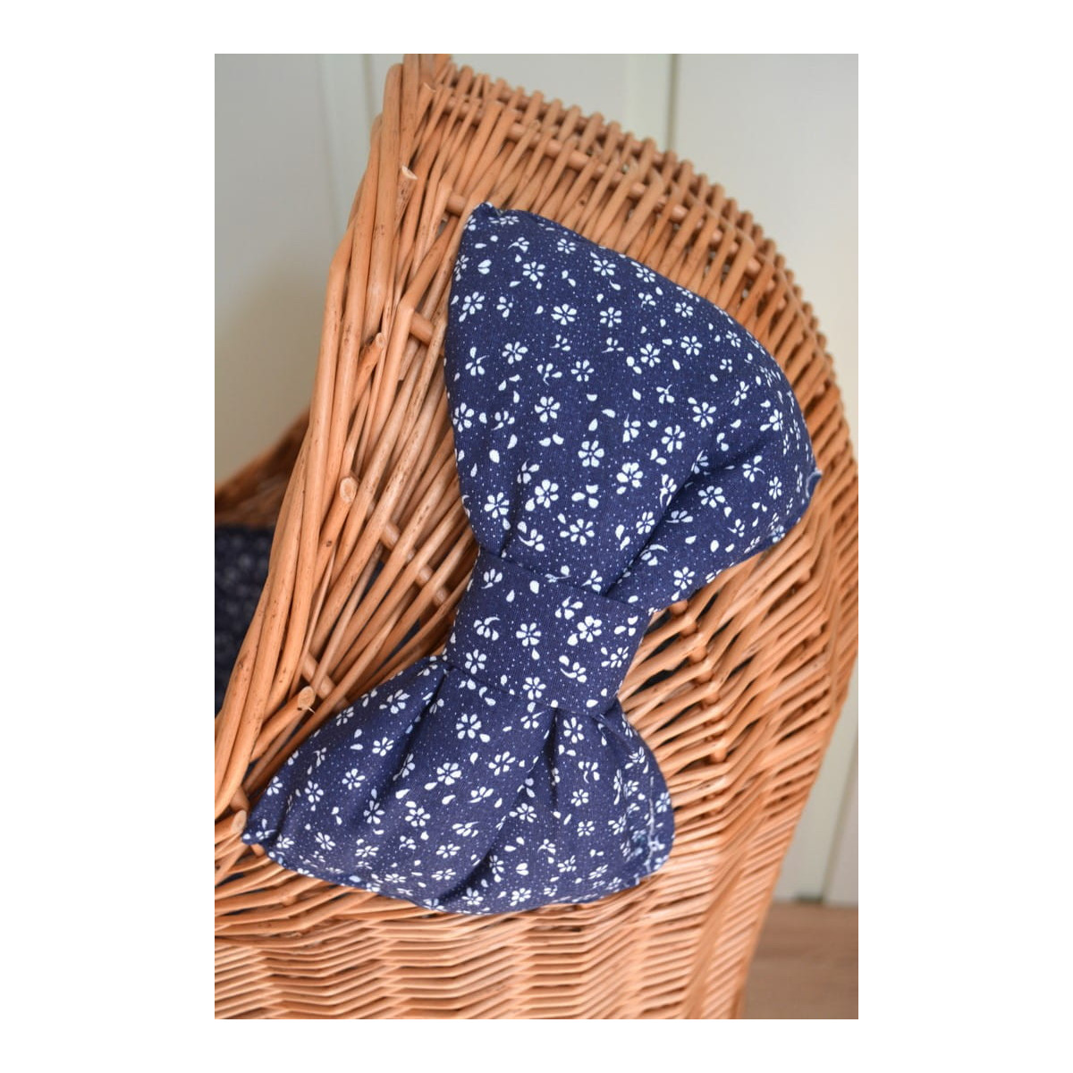 Cărucior din rattan pentru copii, cu fundiță albastră și roți din cauciuc.