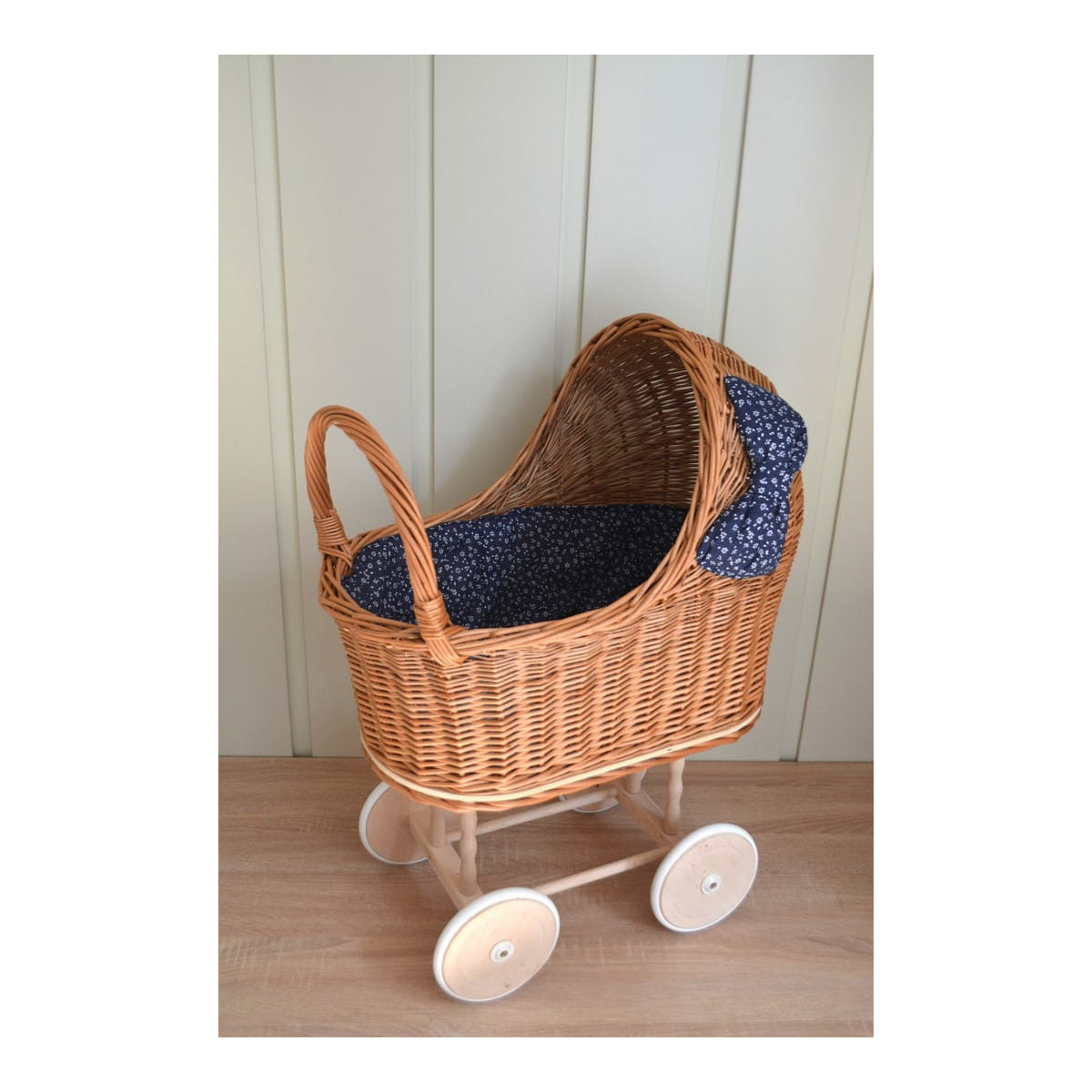 Cărucior din rattan pentru copii, cu fundiță albastră și roți din cauciuc.