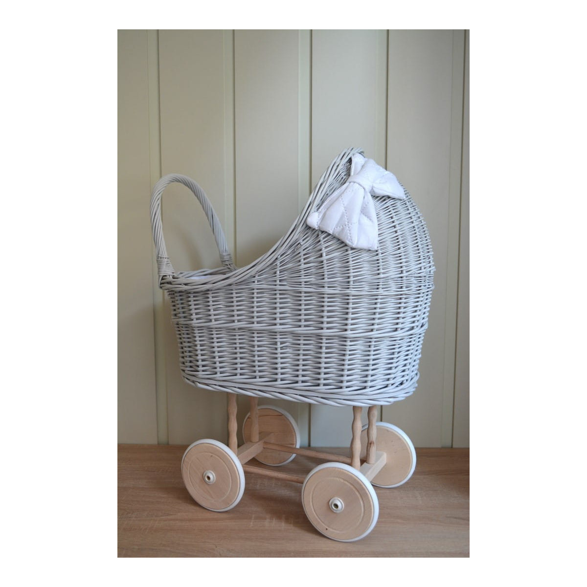Cărucior gri pentru păpuși cu o pătură albă și o fundiță