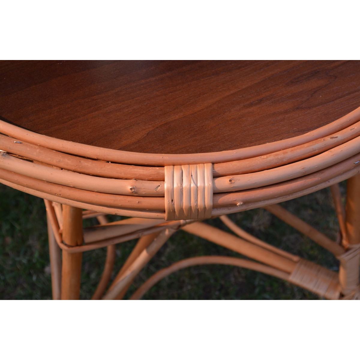 Masă rotundă mare din ratan natural cu blat închis.