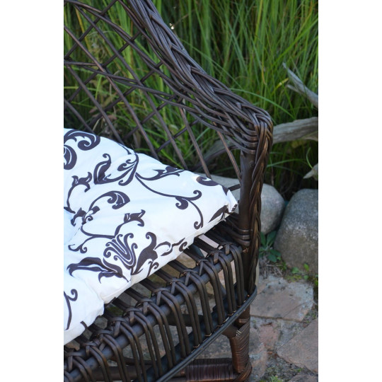 Scaun din ratan maro închis pentru grădină, cu perne albe cu model.