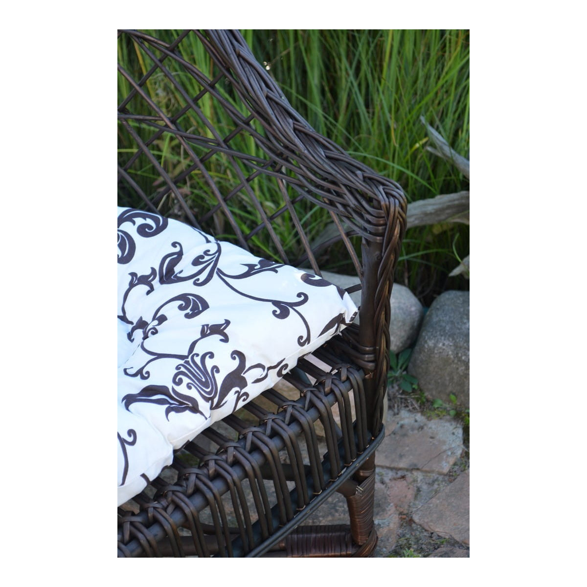 Scaun din ratan maro închis pentru grădină, cu perne albe cu model.