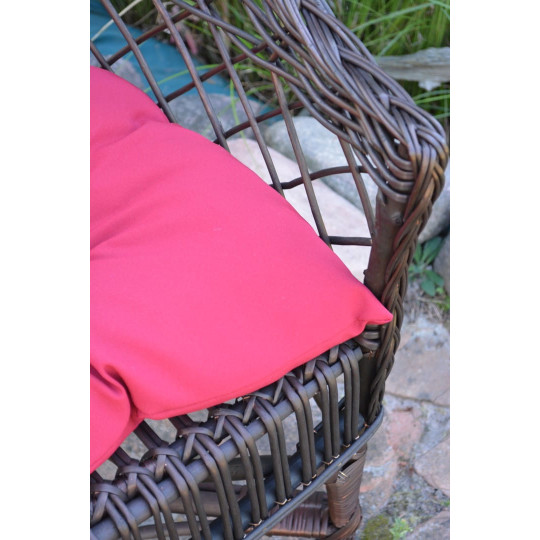 Scaun din ratan de culoare maro închis cu pernă roșie