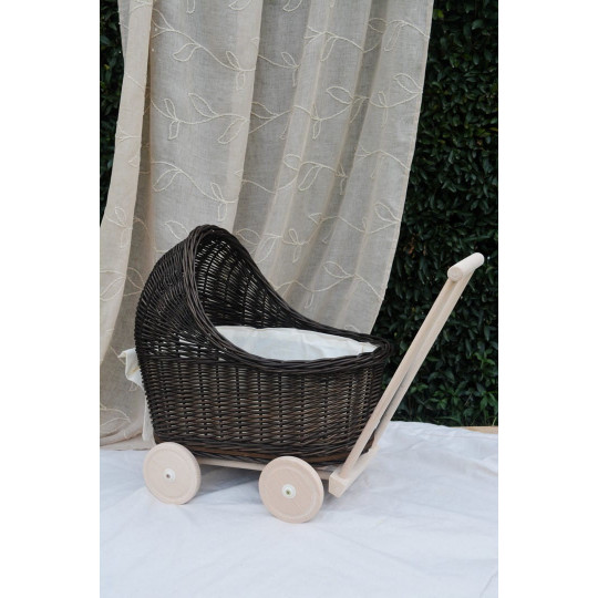 Cărucior pentru copii din rattan original, de culoare brownă, cu o fundiță albă.