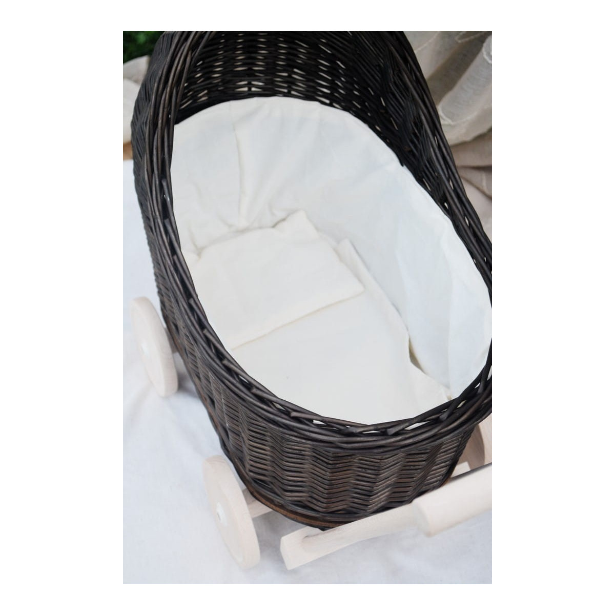 Cărucior pentru copii din rattan original, de culoare brownă, cu o fundiță albă.