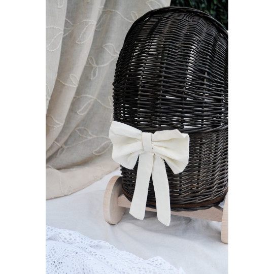 Cărucior pentru copii din rattan original, de culoare brownă, cu o fundiță albă.