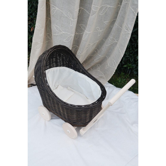 Cărucior pentru copii din rattan original, de culoare brownă, cu o fundiță albă.