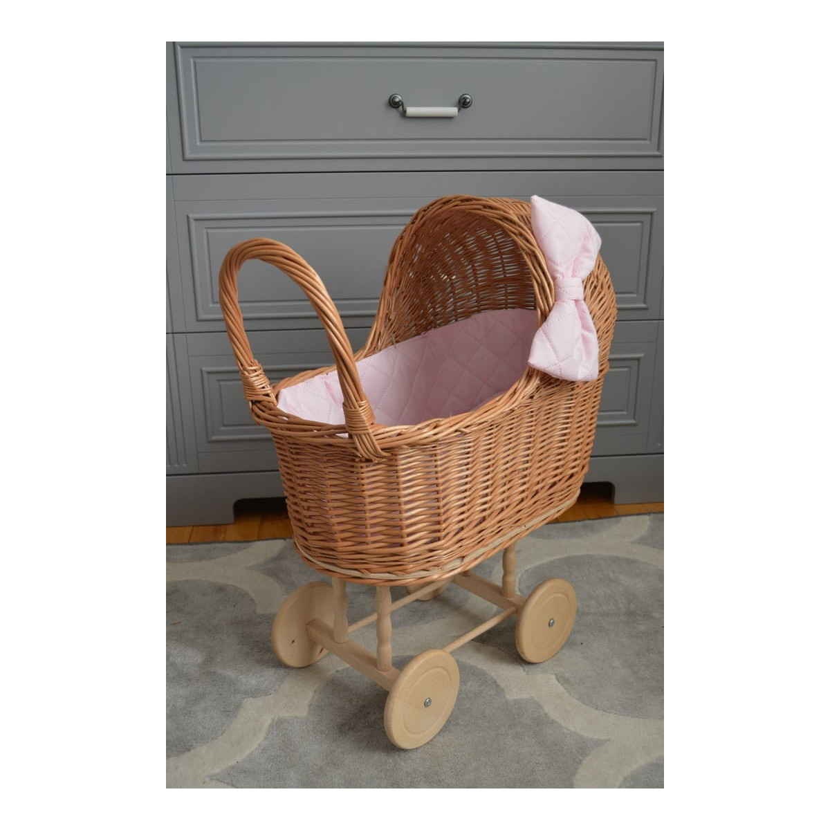 Cărucior pentru păpuși țesut manual, cu umplutură roz și fundiță.