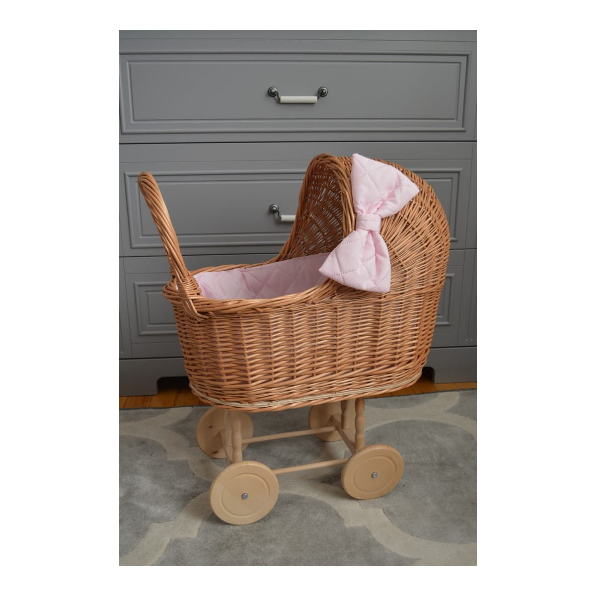 Cărucior pentru păpuși țesut manual, cu umplutură roz și fundiță.
